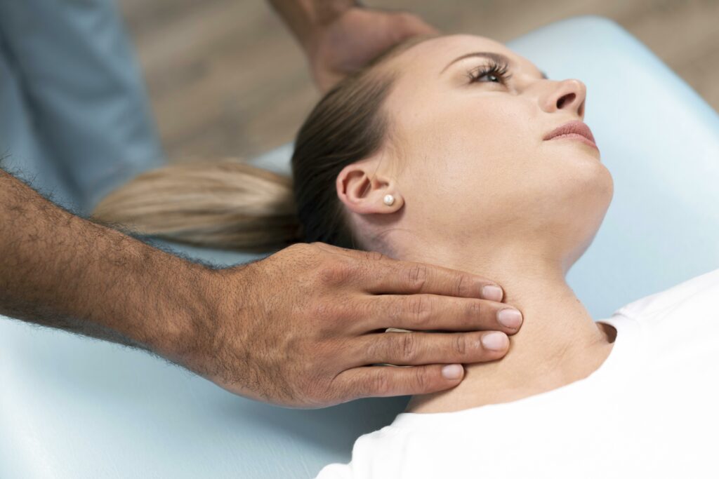 Un kiné pratique un massage du cou sur une patiente allongée. 