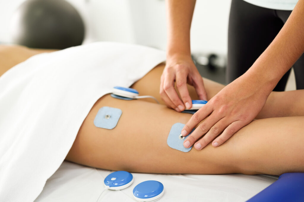 Un kiné applique des électrodes sur la cuisse d'une patiente afin de provoquer une électrostimulation. 