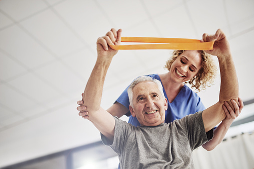 une séance de kinésithérapie gériatrique, avec une personne âgée accompagné d'un masseur-kinésithérapeute.